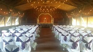 Dance Hall Wedding - chairs with white covers/purple accent facing a stage where a wedding will occur
