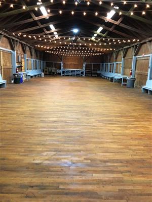 Dance Hall - open space with wood floor, lights draped across room, small stage at far end, bench